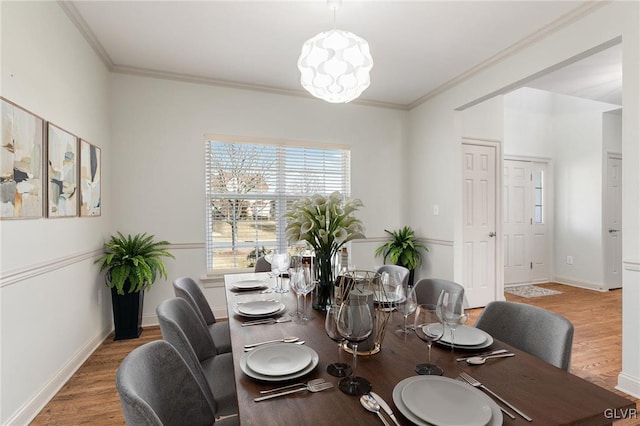 dining room featuring crown molding, baseboards, and wood finished floors