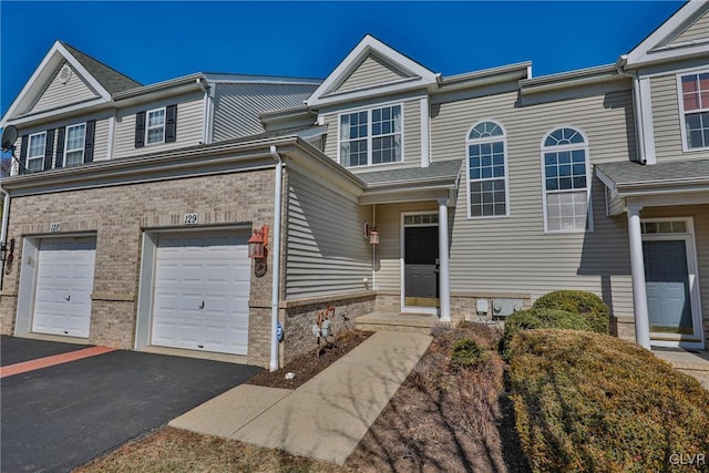 townhome / multi-family property featuring a garage, brick siding, and driveway