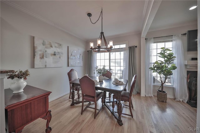 dining area featuring light wood-style flooring, baseboards, an inviting chandelier, and ornamental molding