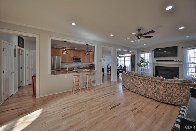 living area featuring recessed lighting, ornamental molding, a ceiling fan, and light wood finished floors