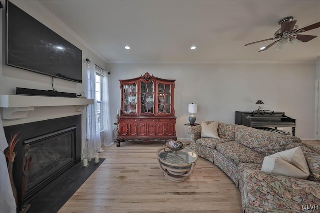 living room with a fireplace with flush hearth, recessed lighting, crown molding, and wood finished floors