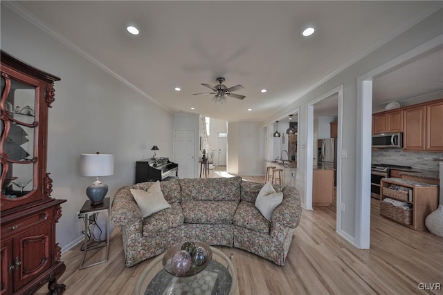 living area with baseboards, ceiling fan, ornamental molding, recessed lighting, and light wood-style flooring