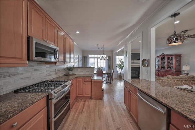 kitchen with backsplash, appliances with stainless steel finishes, a peninsula, crown molding, and light wood finished floors