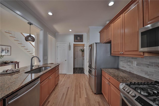 kitchen with brown cabinets, a sink, stainless steel appliances, light wood-style floors, and crown molding