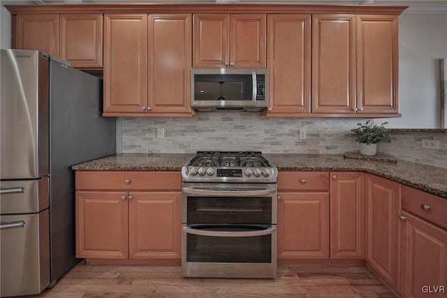 kitchen with decorative backsplash, dark stone counters, and appliances with stainless steel finishes