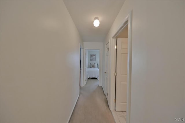 corridor featuring baseboards and light colored carpet