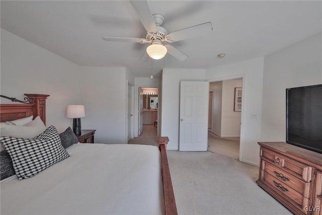 bedroom with baseboards, light carpet, ensuite bath, and ceiling fan