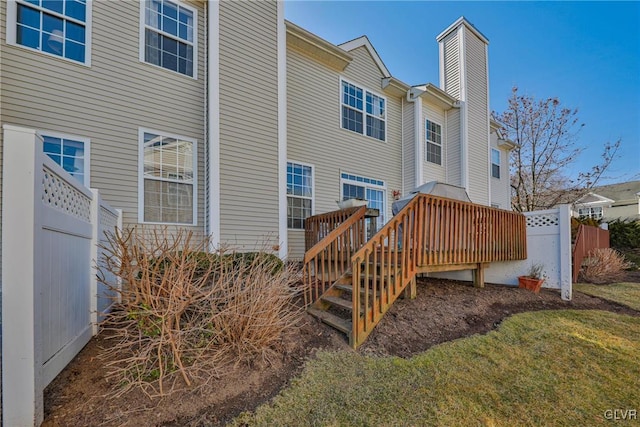 back of property with a wooden deck, fence, and a chimney