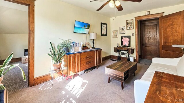 carpeted living area with a ceiling fan and baseboards