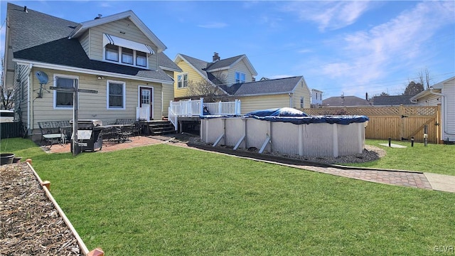 back of house featuring a yard, a fenced in pool, a shingled roof, and fence