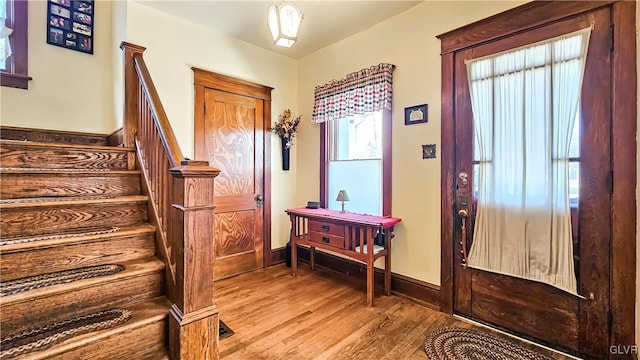 entryway with stairway, baseboards, and wood finished floors