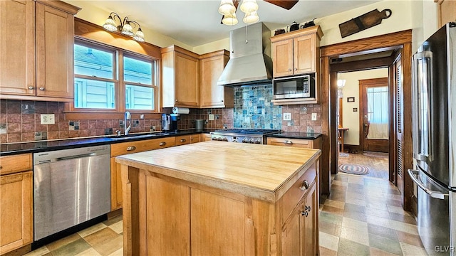 kitchen featuring butcher block countertops, a sink, appliances with stainless steel finishes, wall chimney range hood, and light floors