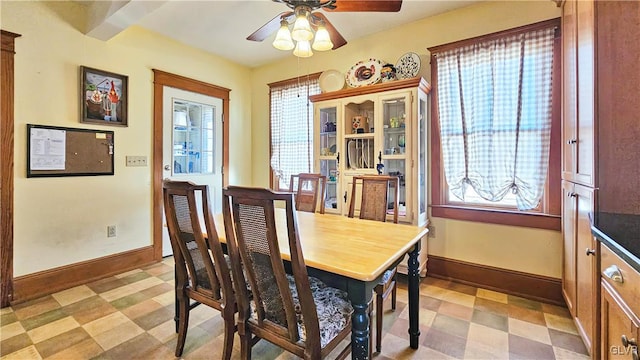 dining room featuring a ceiling fan, light floors, and baseboards