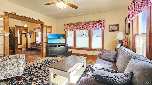 living area featuring a ceiling fan, stairway, wood finished floors, and baseboards