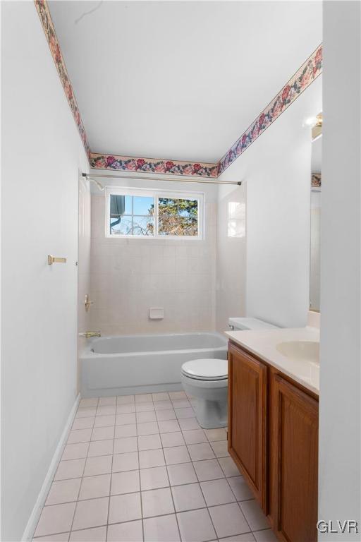 bathroom featuring tile patterned floors, toilet, washtub / shower combination, baseboards, and vanity