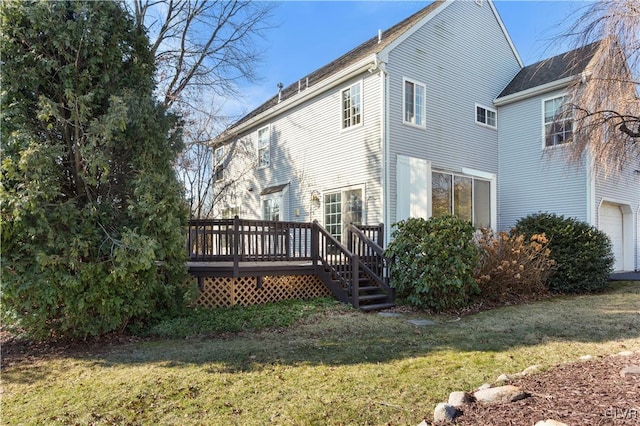 rear view of property featuring a lawn, a deck, and an attached garage