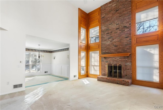 unfurnished living room featuring a high ceiling, a brick fireplace, carpet, and visible vents