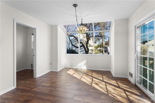 unfurnished dining area featuring an inviting chandelier, baseboards, and wood-type flooring