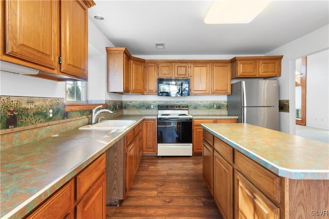 kitchen featuring brown cabinetry, electric range, freestanding refrigerator, a sink, and black microwave