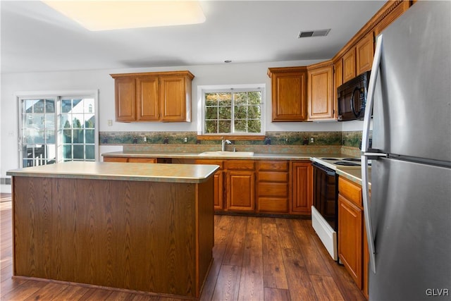 kitchen featuring visible vents, black microwave, freestanding refrigerator, electric range, and a sink