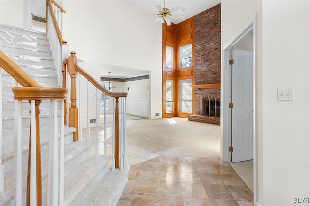 interior space featuring a fireplace, a ceiling fan, and a towering ceiling