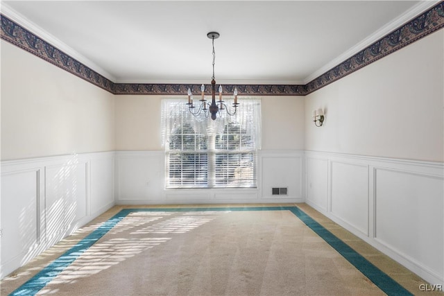 unfurnished dining area with visible vents, light colored carpet, a chandelier, and wainscoting