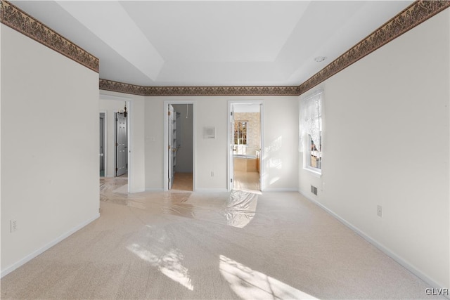 unfurnished room featuring a tray ceiling, baseboards, and carpet flooring