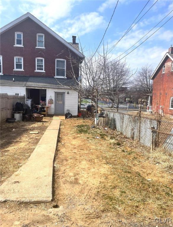 rear view of property featuring a chimney and fence