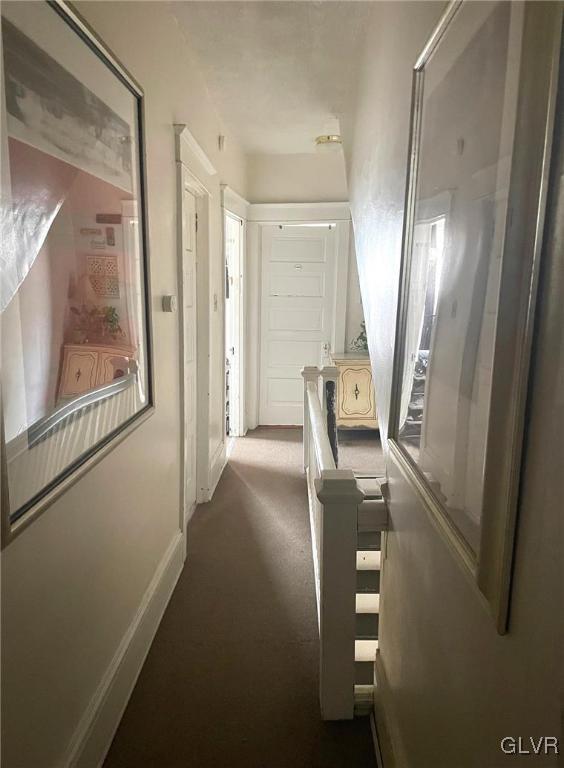 hall featuring an upstairs landing, carpet, and baseboards