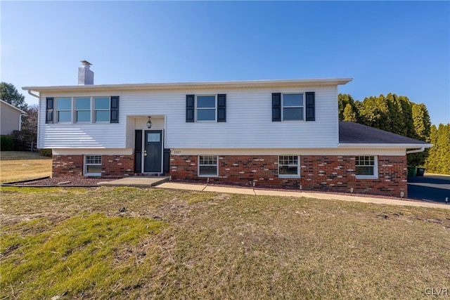 split foyer home with a front yard, brick siding, and a chimney