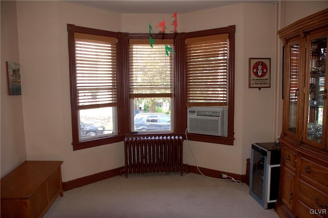 interior space featuring cooling unit, baseboards, light colored carpet, and radiator heating unit