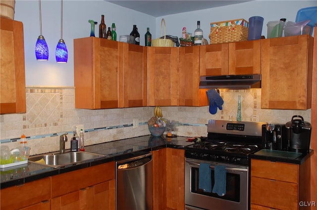 kitchen with dark countertops, under cabinet range hood, brown cabinetry, stainless steel appliances, and a sink