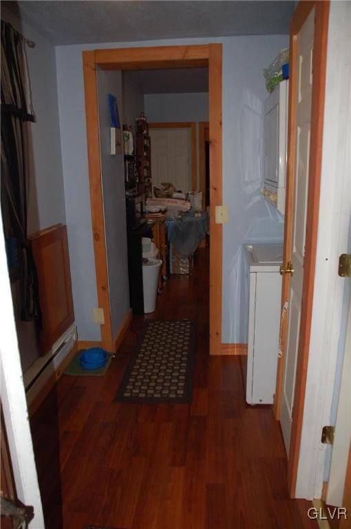 corridor with stacked washing maching and dryer and wood finished floors