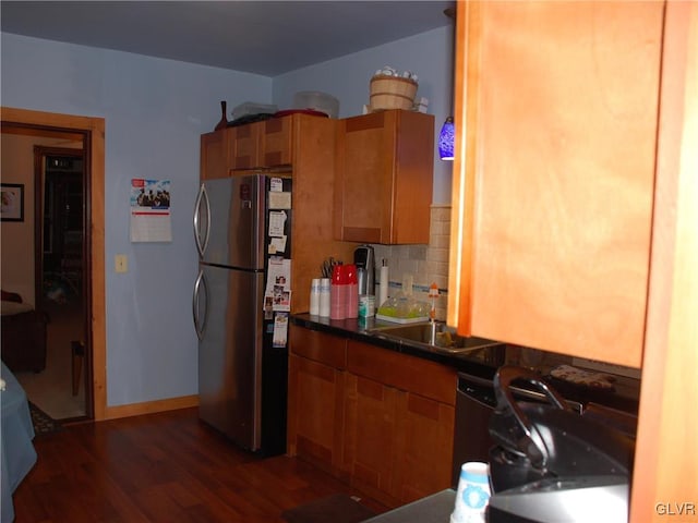 kitchen featuring brown cabinetry, decorative backsplash, freestanding refrigerator, and wood finished floors