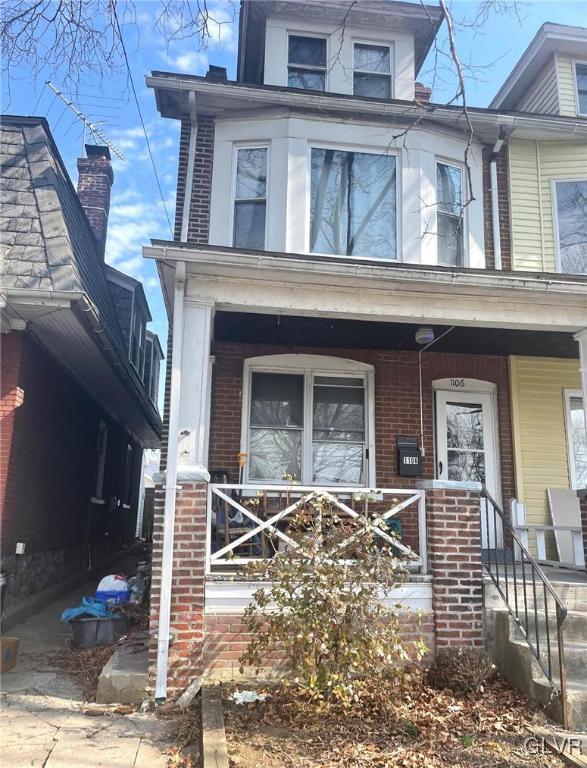 american foursquare style home with a porch and brick siding