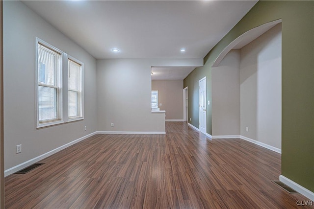 unfurnished room featuring visible vents, baseboards, and dark wood finished floors