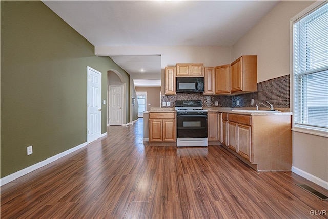 kitchen with black microwave, dark wood finished floors, range with gas stovetop, decorative backsplash, and a sink