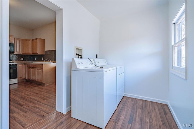 washroom with dark wood-type flooring, a sink, separate washer and dryer, baseboards, and laundry area