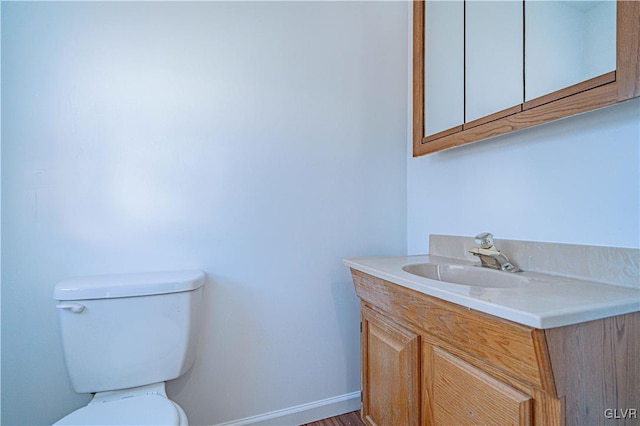 bathroom featuring baseboards, toilet, and vanity