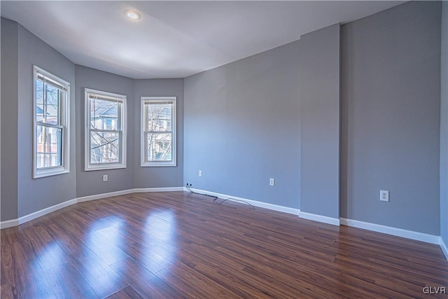 empty room with dark wood finished floors and baseboards