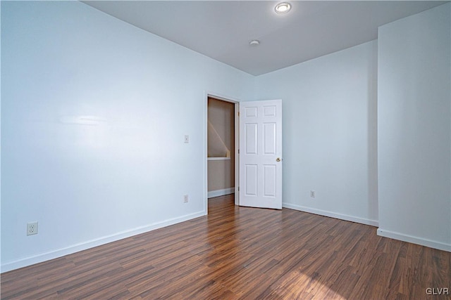 unfurnished room with baseboards and dark wood-style flooring