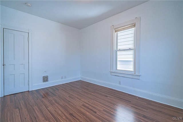 empty room with visible vents, baseboards, and dark wood-style flooring