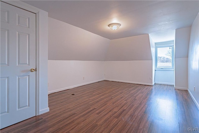 bonus room with dark wood-style floors, baseboards, and lofted ceiling