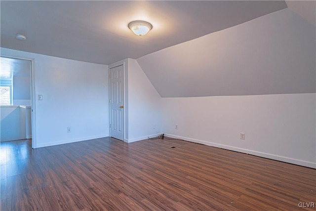 bonus room featuring dark wood finished floors, baseboards, and vaulted ceiling