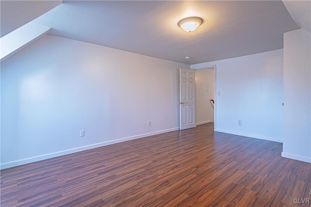 spare room with baseboards and dark wood-style flooring