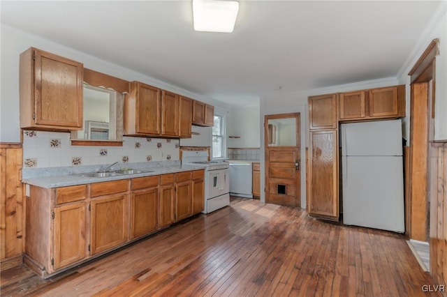 kitchen with hardwood / wood-style floors, white appliances, a sink, light countertops, and brown cabinets