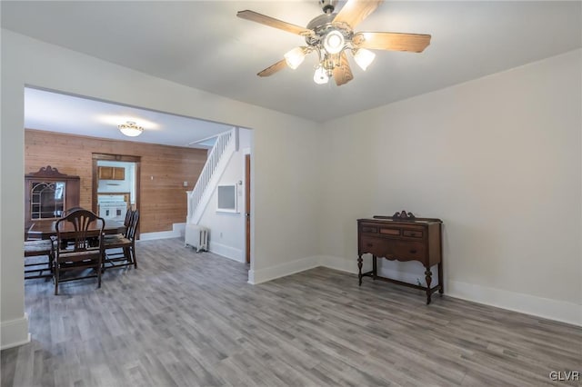 dining area featuring wooden walls, stairs, baseboards, and wood finished floors