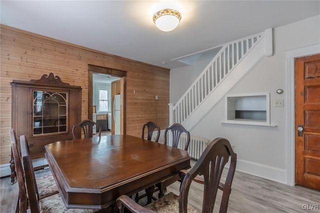 dining space featuring wooden walls, stairs, baseboards, and wood finished floors