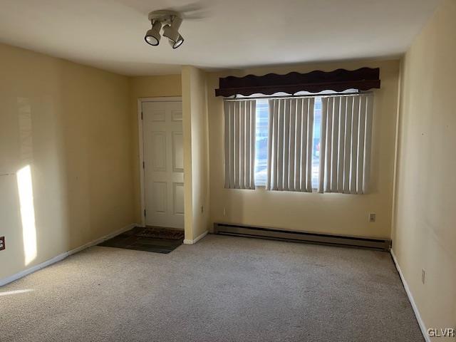 unfurnished room featuring carpet flooring, baseboards, and a baseboard radiator