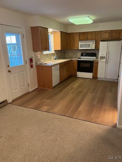 kitchen with white appliances, tasteful backsplash, brown cabinets, and wood finished floors